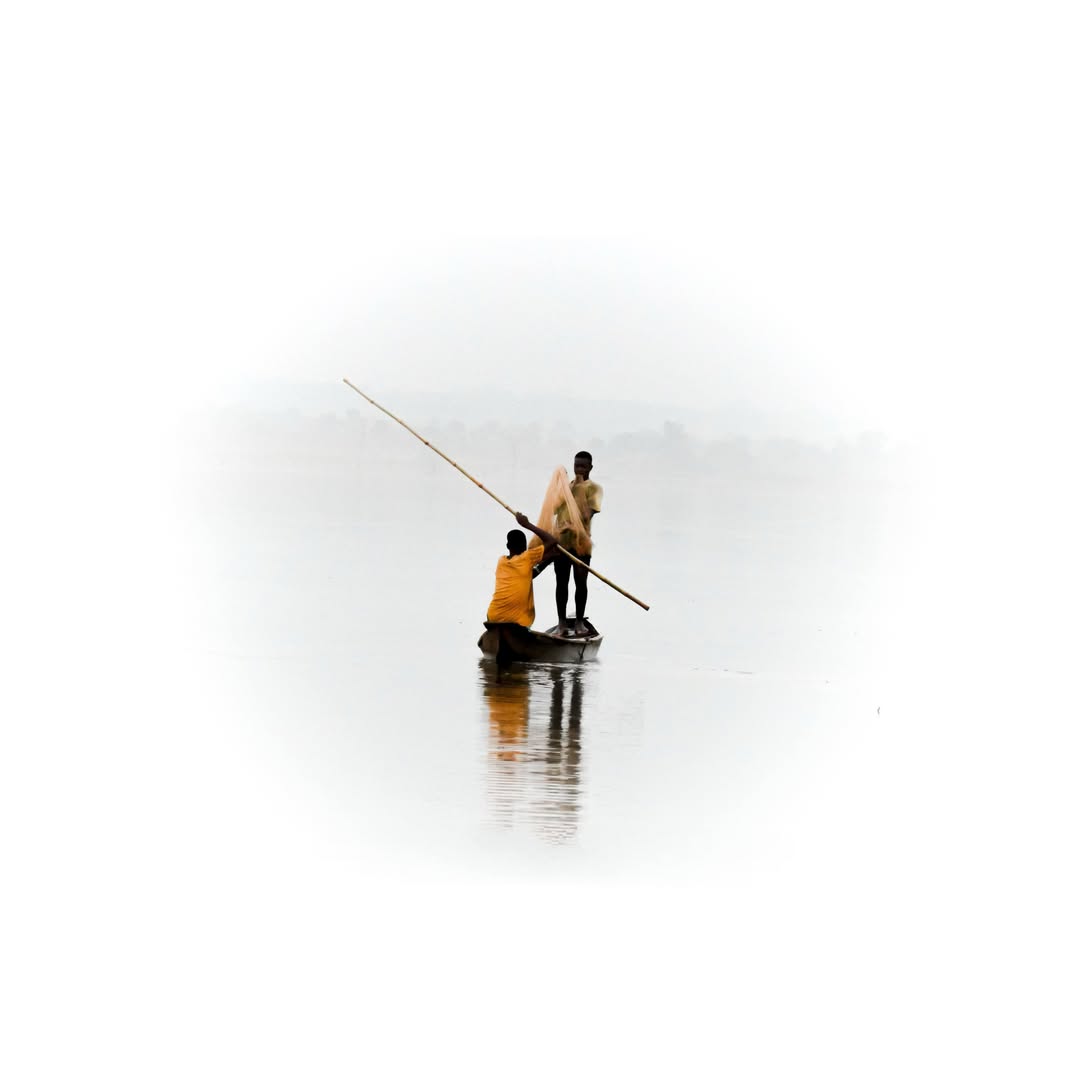 Fishermen pulling a net from a boat reflected on still water